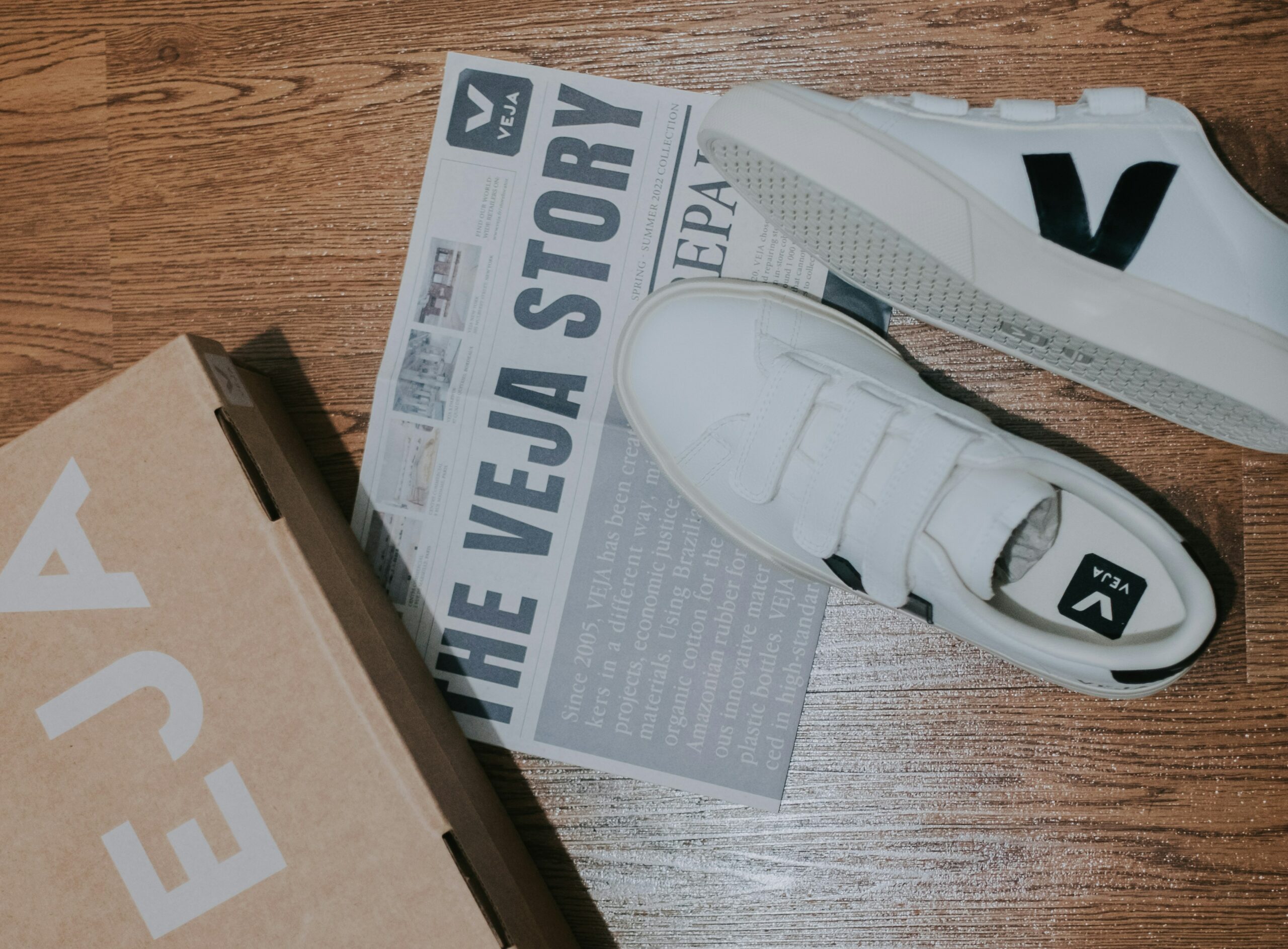 Veja Shoes stlized with the product box and a newspaper pamphlet describing the story of Veja