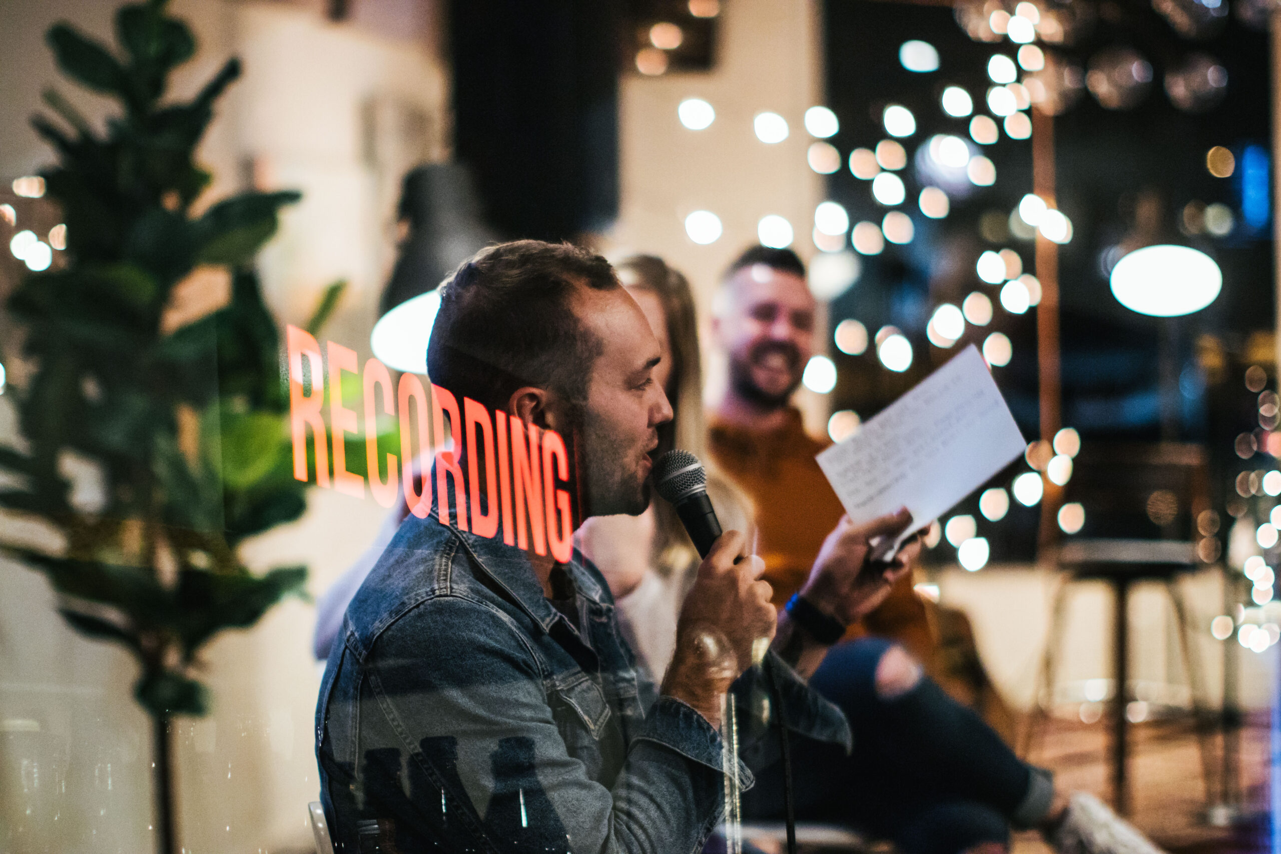 Dual exposure of a recording sign over someone speaking into a microphone during a podcast recroding