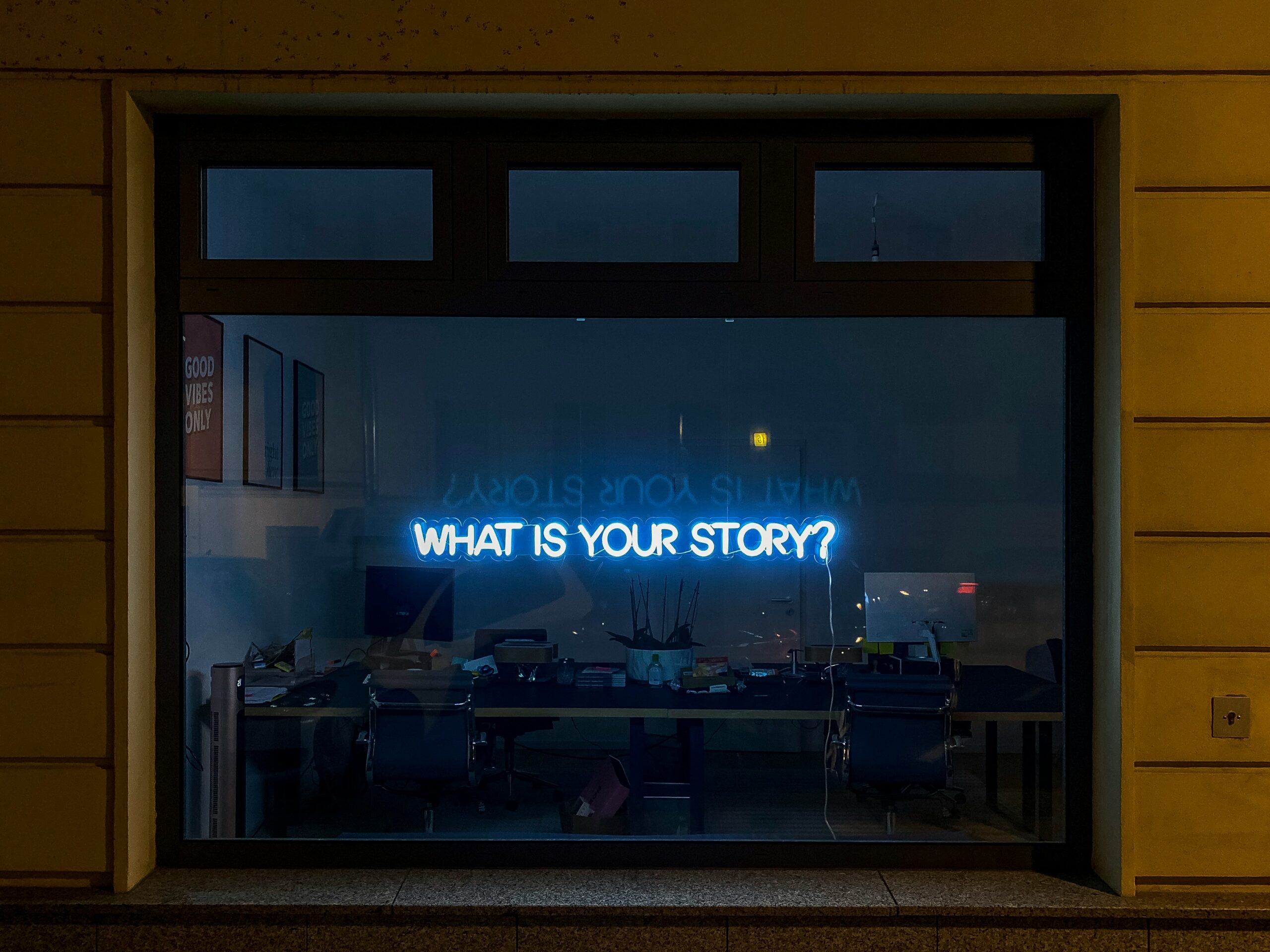 Photo with a neon sign saying "what is your story"