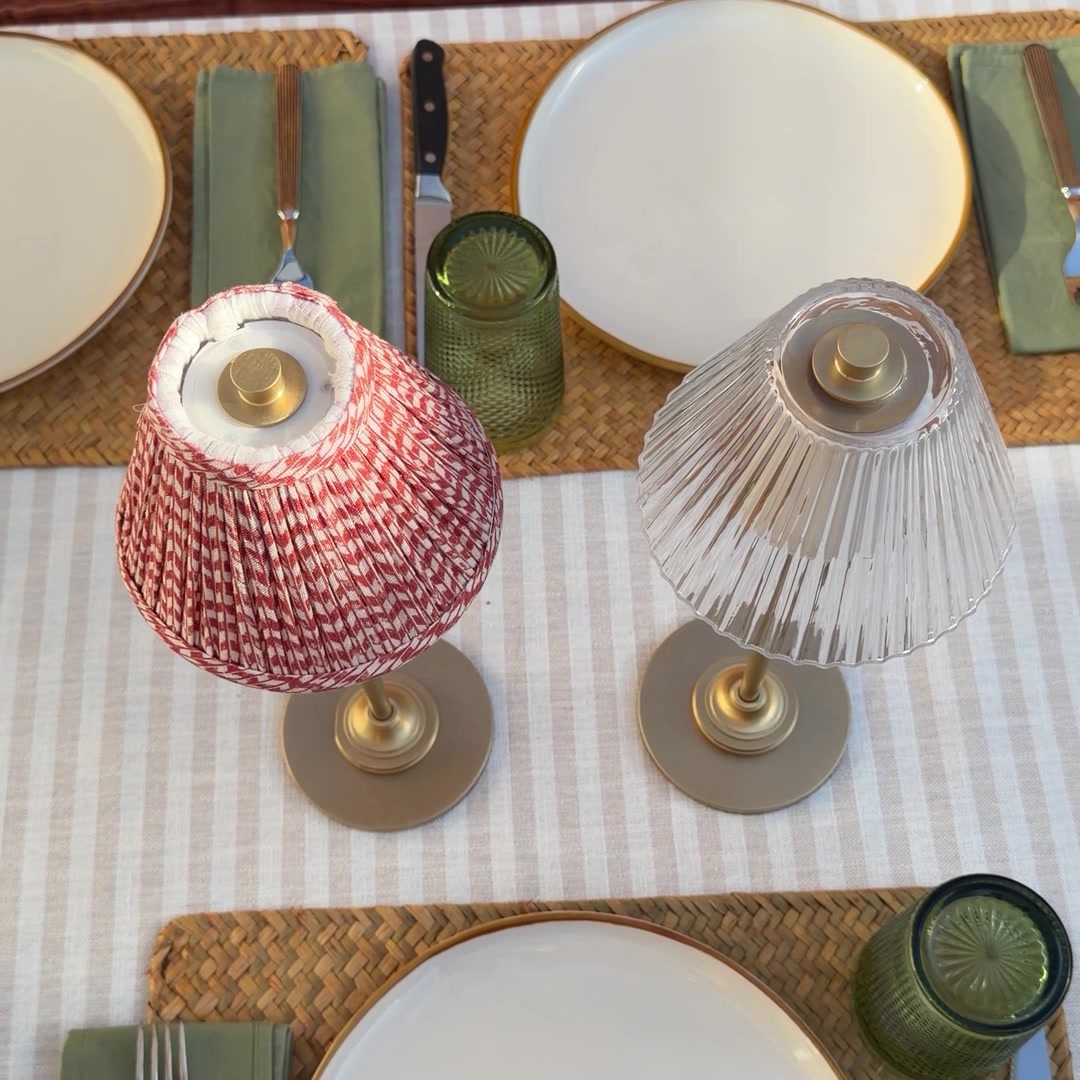 Red pleated and fluted glass Corston rechargeable lamps on a table set for dinner.